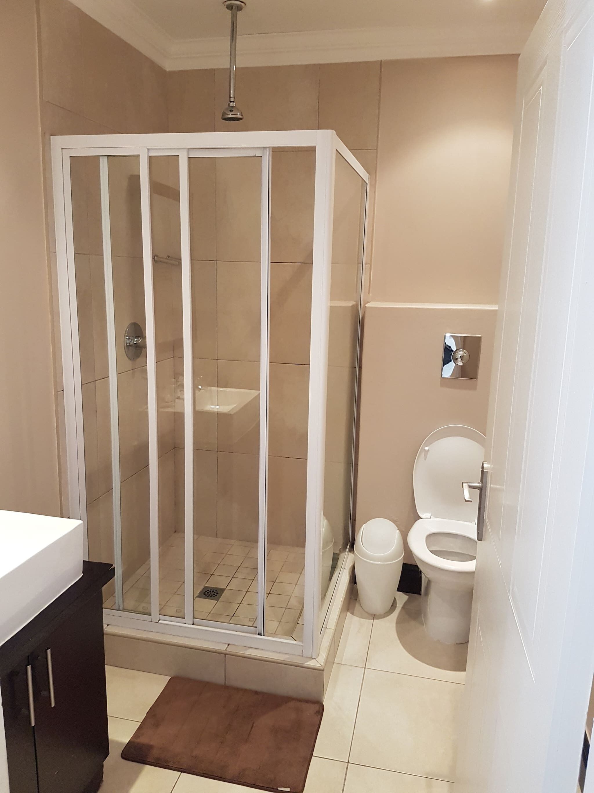 A bathroom with a glass-enclosed shower, a toilet, and a sink.