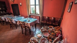 Un comedor con varias mesas dispuestas, cubiertas con manteles a cuadros, sillas de madera y una variedad de alimentos.