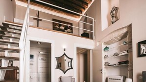Un loft espacioso con techo alto, un nivel entre piso, un espejo grande y una escalera moderna.