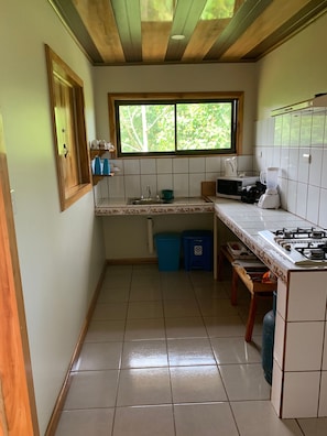 A compact kitchen with a window, a microwave, a gas stove, and a sink.