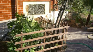 A garden area with a wooden fence, potted plants, and a brick wall. - Sa Domu Sarda - Apartment With Terrace 2 (Piscinas)