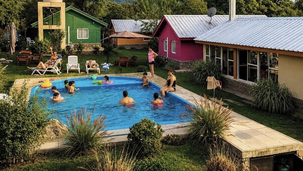 Une piscine entourée de maisons, où l’on peut voir des gens nager et se détendre.