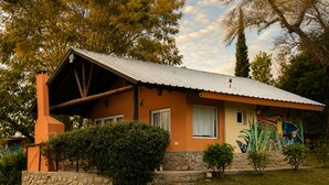 Une maison avec un toit en pente, une cheminée et un mur de pierre à l’avant.