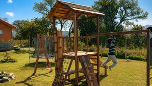 Une structure de jeu en bois, dotée d’un mur d’escalade et d’un toboggan.