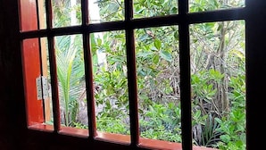 Une fenêtre à carreaux multiples, chacun offrant une vue sur une végétation luxuriante et diverses plantes.