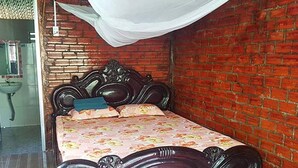 Une pièce avec un mur en briques, un lit recouvert d’une courtepointe à motifs floraux et un baldaquin blanc.