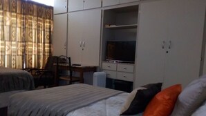 A hotel room with a bed, a desk, a chair, and a television. - Casa Villa Guest House Carletonville - Suite 4 (Merafong City)