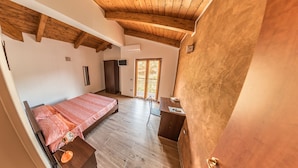 Un dormitorio con cama, escritorio y silla. Se ve una ventana con vista al exterior.