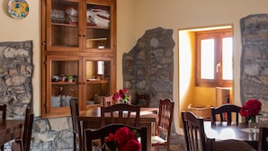 Un comedor con un aparador de madera, paredes de piedra y una ventana que deja entrar luz natural.
