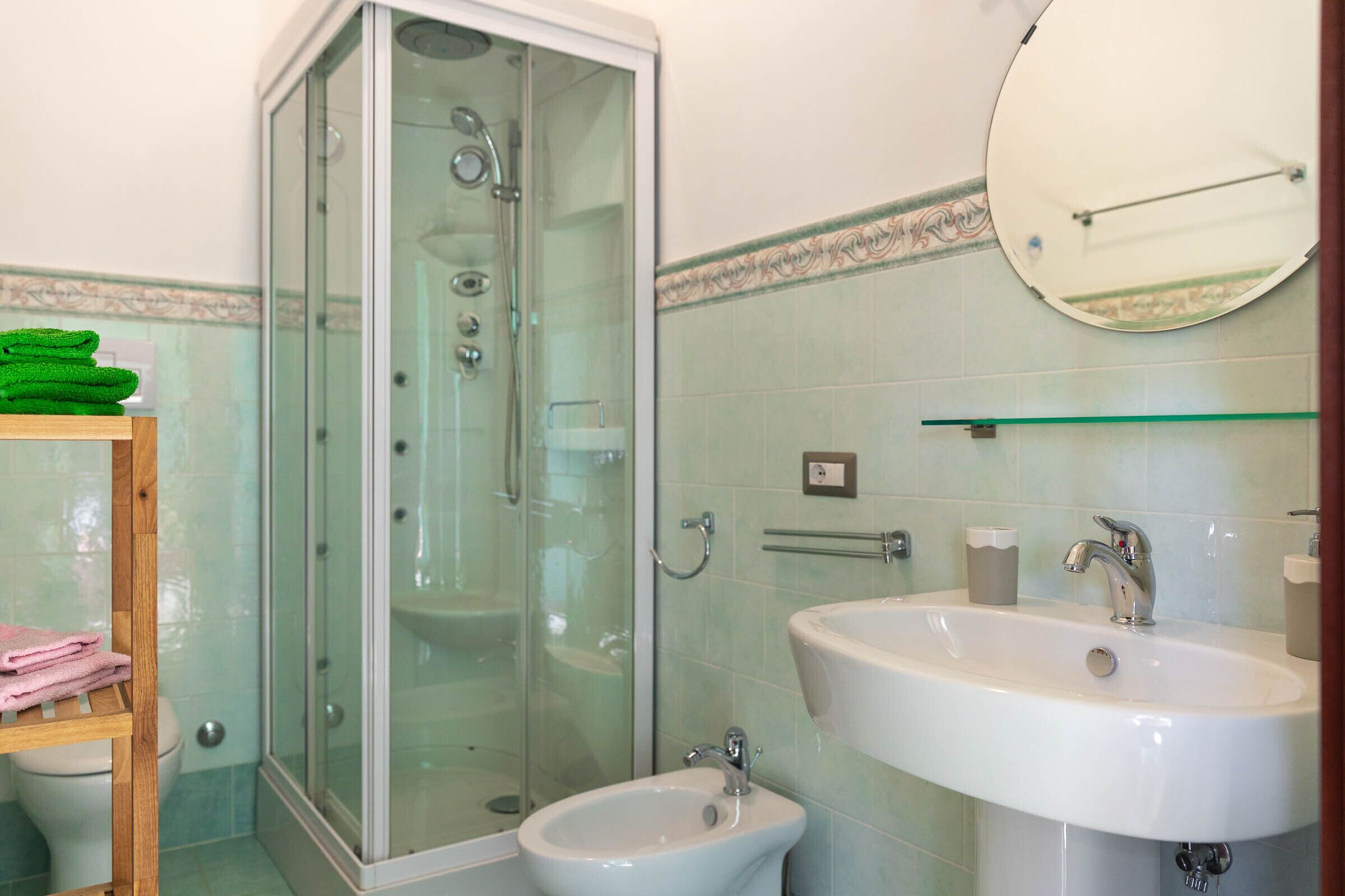 A bathroom with a glass-enclosed shower, a bidet, a sink, and a mirror.