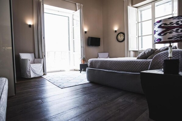 A bedroom with a bed, a TV, a clock, and a window. - Regio Maison du Charme (Cagliari)