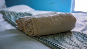 A neatly made bed with rolled towels and a patterned blanket. - Room-relaxing Guest House in th Heart of (Cape Town)