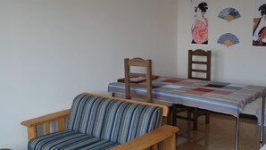A living room with a sofa, a dining table with chairs, and a small table.