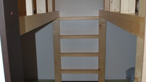 A wooden bunk bed with a pull-up ladder, a wooden shelf, and a small window.