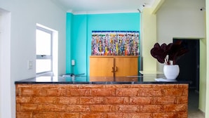A kitchen with a brick-textured island, a teal wall, and a colorful artwork above the cabinets. - Room-relaxing Guest House in the Heart o (Cape Town)