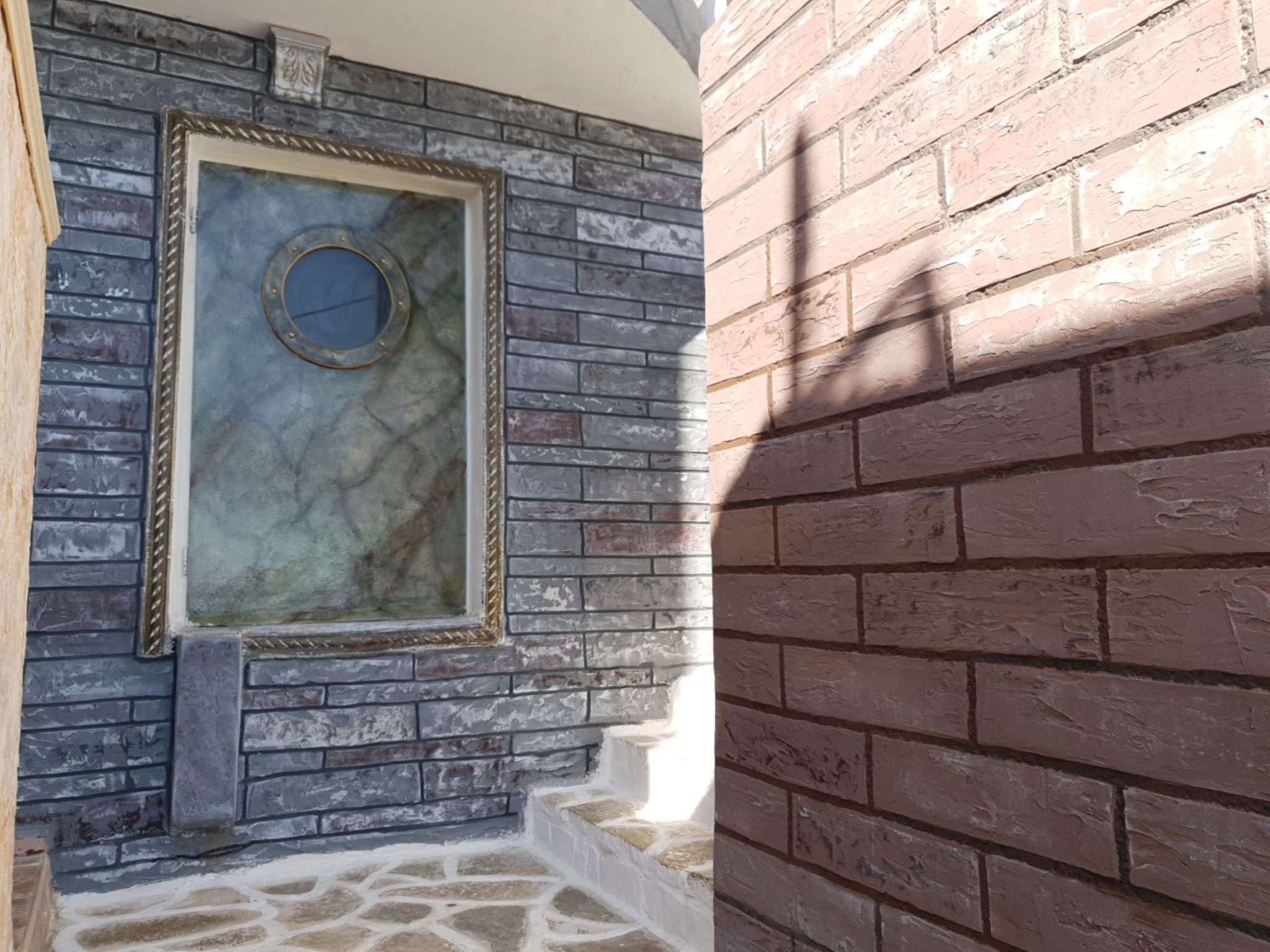 A stone wall with a framed mirror and a stone floor.