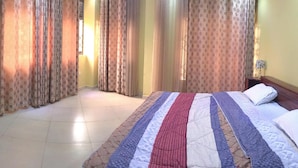 Une chambre d’hôtel avec un grand lit, des rideaux, une table de chevet et une lampe.