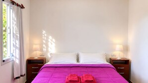 A hotel room with a bed, two bedside tables, a window with curtains, and a view of greenery outside. - Mama Pacha Cabin Rural Nature Retreat Near Salta (Vaqueros)