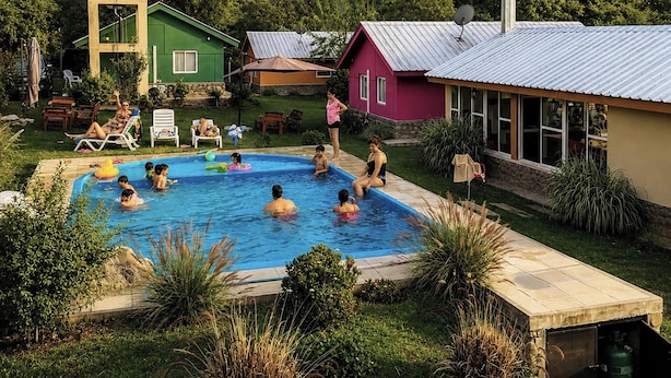 Una piscina rodeada de casas, con gente nadando y descansando.
