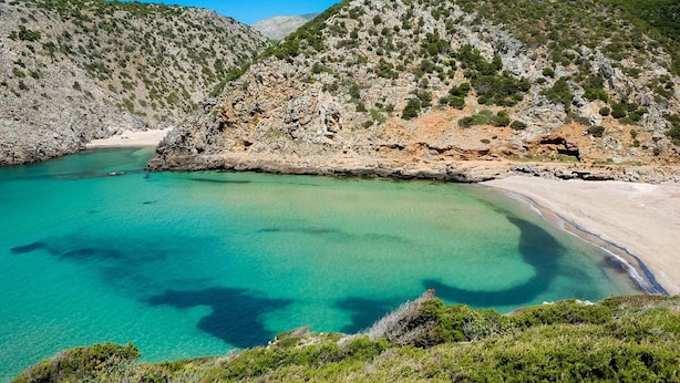 A coastal landscape with clear turquoise waters, rocky cliffs, and sparse vegetation. - Sa Domu Sarda - Two Bedroom Apartment 1 (Piscinas)