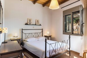Une chambre à coucher comprenant un lit, des tables de chevet, un bureau, une fenêtre avec vue et un ventilateur de plafond.