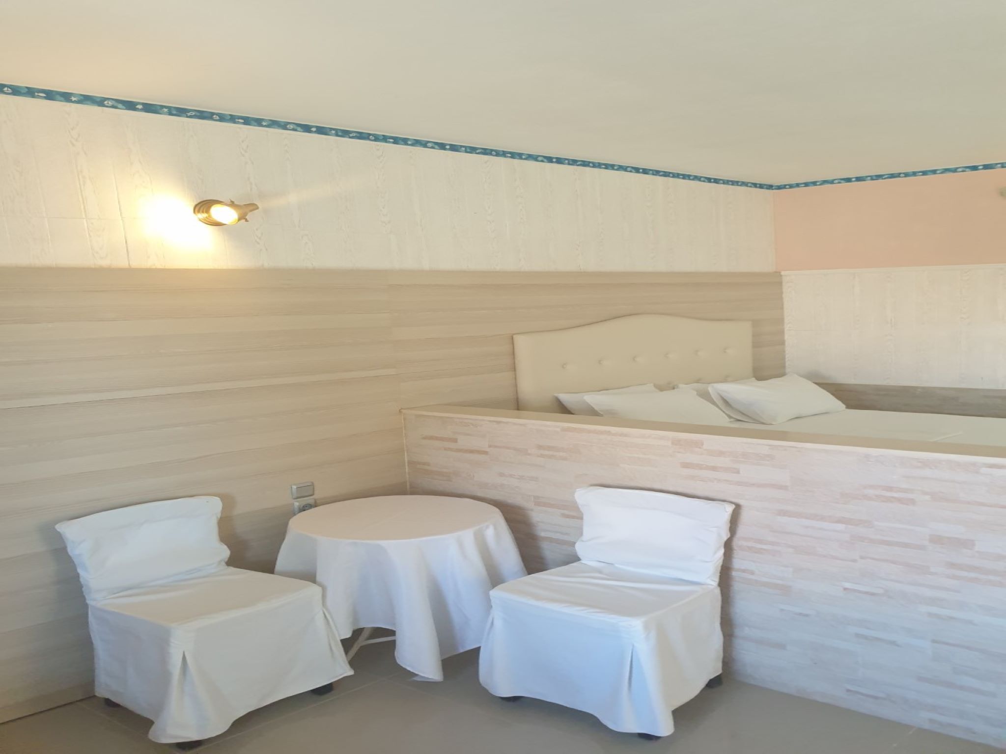 A small, neatly arranged room with a bed, two chairs, and a small table.