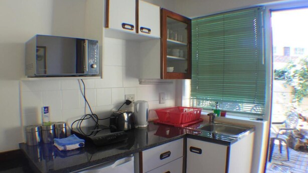 Una cocina compacta con microondas, tostadora y una cesta roja sobre la encimera.