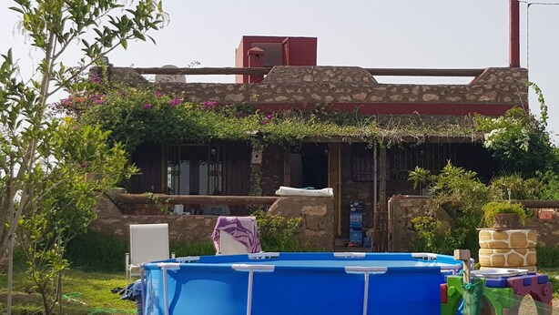 A stone building with a red roof, a blue pool, and a garden with various plants and flowers. - Maison la Branche d Oiseaux (Chaibate)