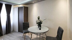 A modern dining area with a round table, two chairs, a vase with flowers, and a patterned rug. - Alessio Premium Rooms - Triple Bedroom (Porec)