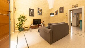 A living room with a sofa, a television, a plant, and artwork on the walls. - Little Home Holidays (Vernole)