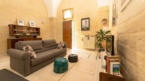 A cozy living room with a sofa, ottoman, and a bookshelf. - Little Home Holidays (Vernole)