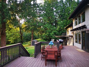 A wooden deck with a table and chairs, surrounded by lush greenery and trees. - Nature House3 Rooms (Issaquah)