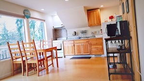 A kitchen with wooden cabinets, a dining table with chairs, a stove, and a television.