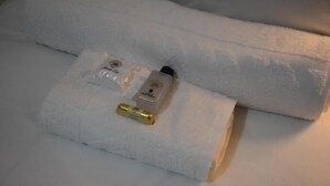 Una toalla blanca doblada con un frasco de loción y una pastilla de jabón encima.