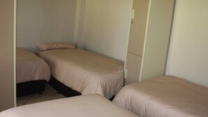 Una habitación con tres camas individuales, cada una con un cabecero a juego.