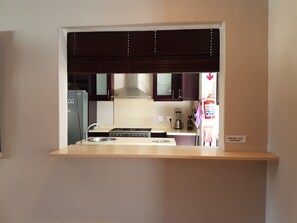 A compact kitchen with a built-in stove, a sink, and dark wooden cabinets. - Fairview Bed And Breakfast - Family Bedroom (Umhlanga)