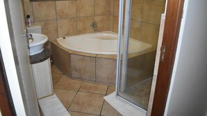 A bathroom with a bathtub, a sink, and a shower enclosure. - Soeteweide North Bb (George)