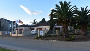 A building with a gated entrance, palm trees, and flags. - Soeteweide North Bb (George)