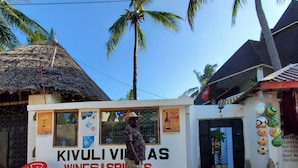 A kiosk named "KIVULI VIVAS WINES&SPIRITS" with a thatched roof and a signboard advertising various products. - Room in Guest Room - A Wonderful Beach Property in Diani Beach Kenya - a Dream Holiday Place (Mombasa)