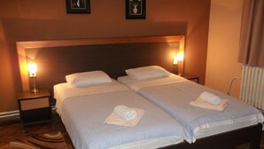 Ein Doppelbett mit zwei Kissen und gefaltetem Handtuch auf jeder Seite. Zwei Nachttische mit Lampen sind vorhanden.