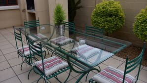 A glass-top table with green metal chairs and striped cushions, surrounded by small potted plants. - Soeteweide North Bb (George)