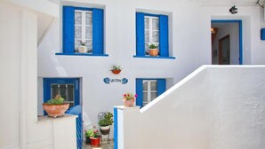 A white building with blue shutters, a welcome sign, and potted plants. - Villa Yiannoula With Amazing sea View at Skopelos Old Port !!! (Skopelos)
