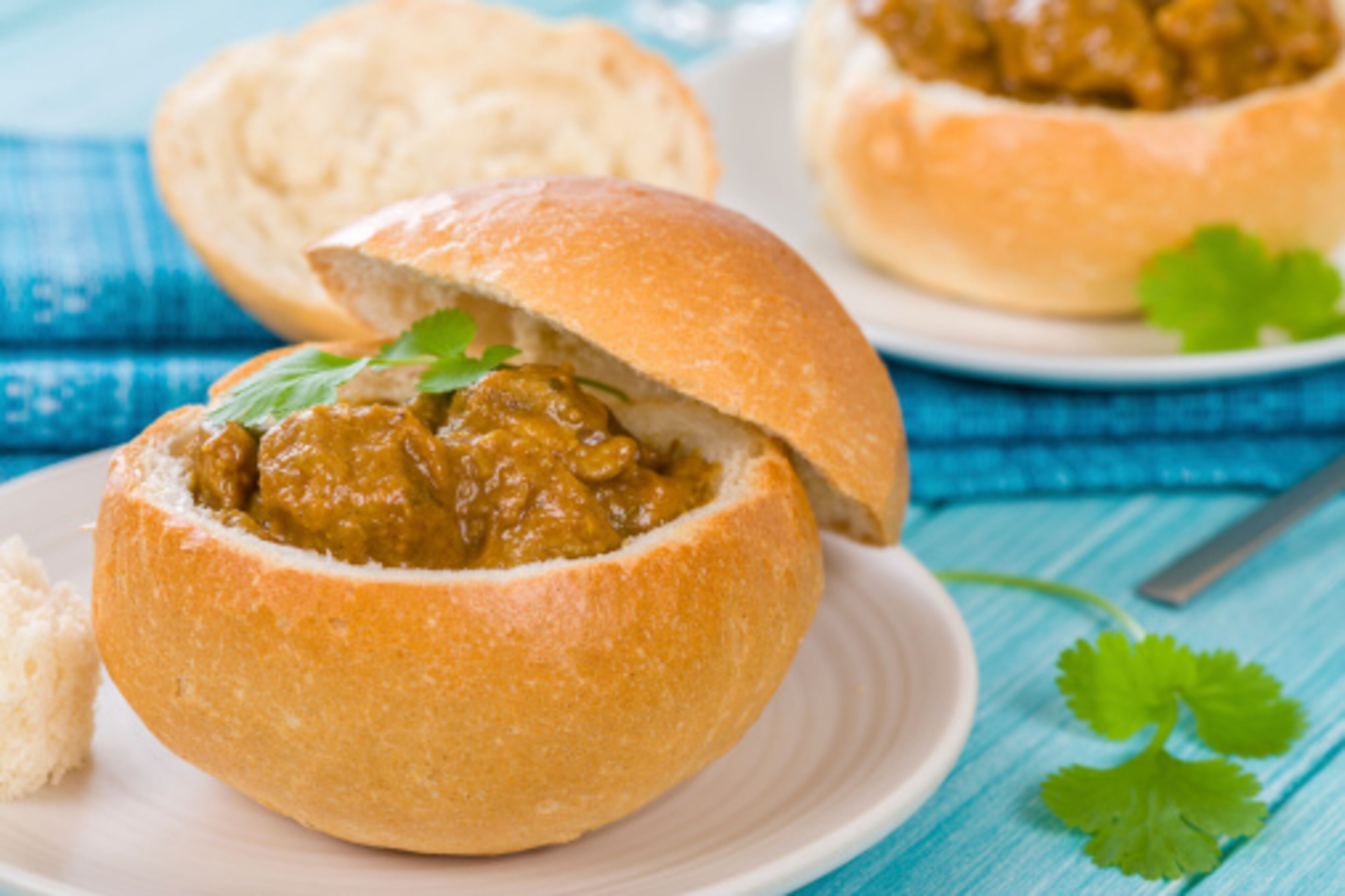 A food item in a bun on a plate with a blue background.