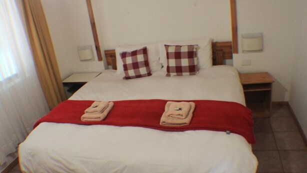 Ein Hotelzimmer mit einem großen Bett, zwei Nachttischen und einer roten Decke.