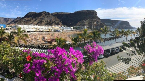 A coastal view with a beach, mountains, and a hotel with white buildings. - Harbour 374 With Private Roof Terrace in Puerto de Mogan (Mogan)