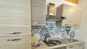 Una cocina moderna con armarios de madera clara, una estufa a gas y un salpicadero decorativo.