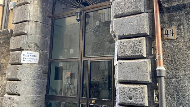 Una entrada con arco de piedra a un edificio, con un letrero que indica que es un albergue para estudiantes.
