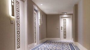 A hallway with patterned carpet, white walls, and doors with decorative panels.