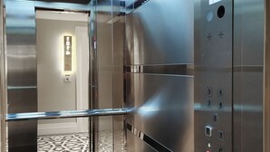 An elevator interior with metallic walls, a digital display showing the number 5, and a patterned floor.