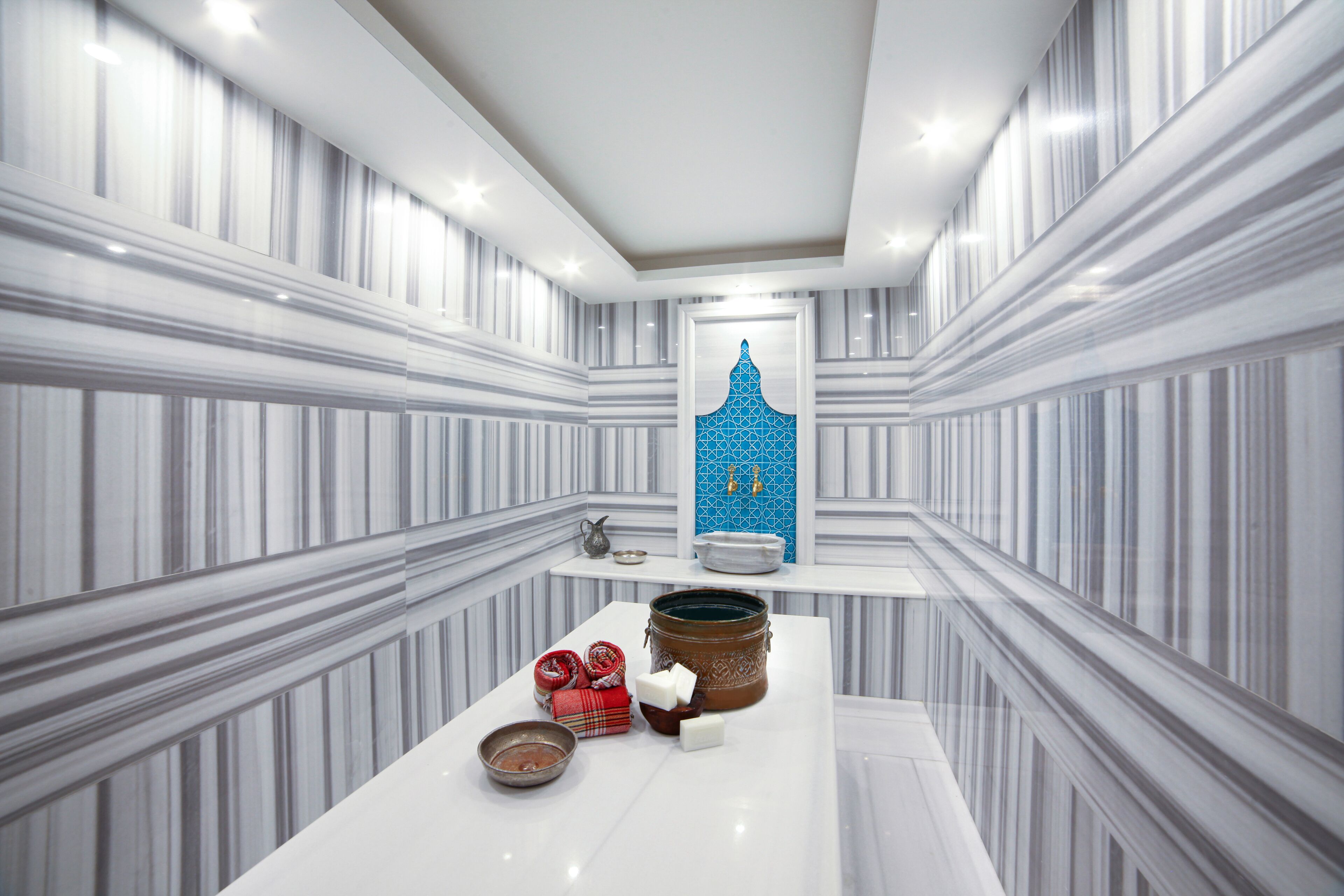 A modern bathroom with striped marble walls, a central sink, and a blue geometric wall art piece.